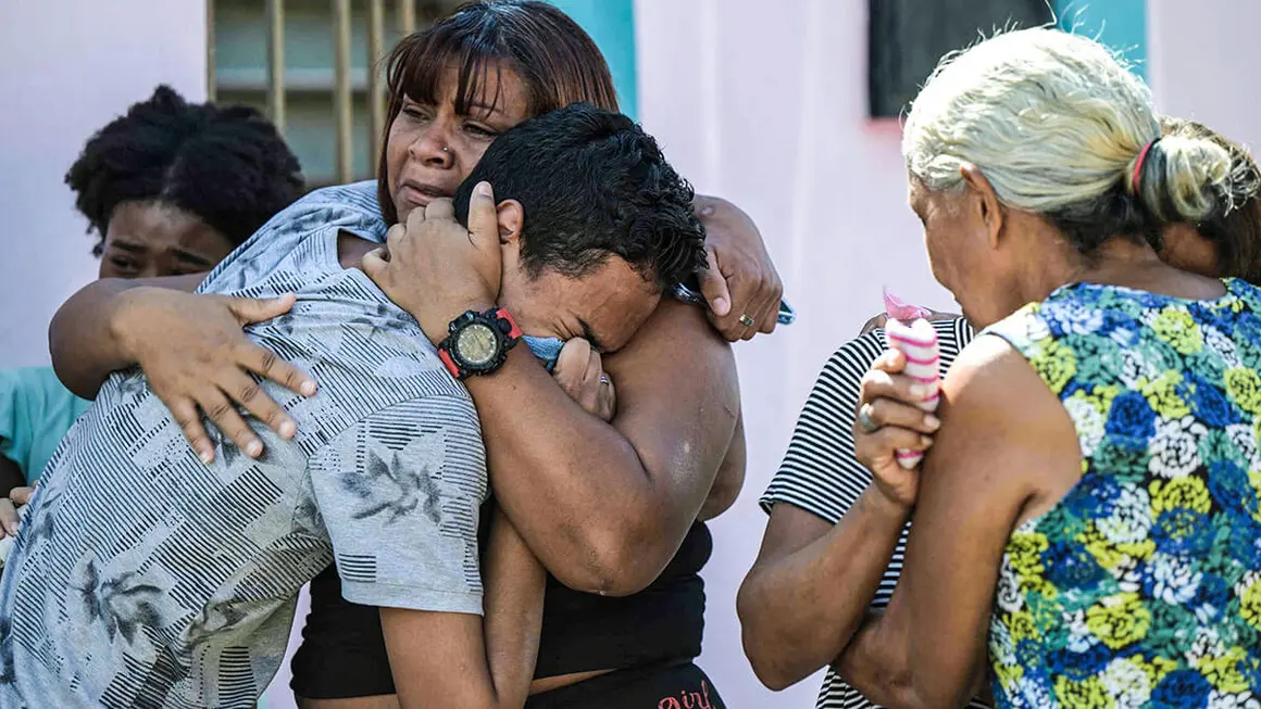 <p>Familiares de Víctor Alfonzo Bustos, de 35 años, se consuelan mientras reciben el ataúd con los restos de su ser querido para su velorio en su casa en Valencia, estado Carabobo, Venezuela, el 31 de julio de 2024. Según su familia, Bustos murió el 30 de julio mientras participaba en una protesta contra los resultados de las elecciones presidenciales de Venezuela que fue reprimida por la policía - AFP/YURI CORTEZ</p>