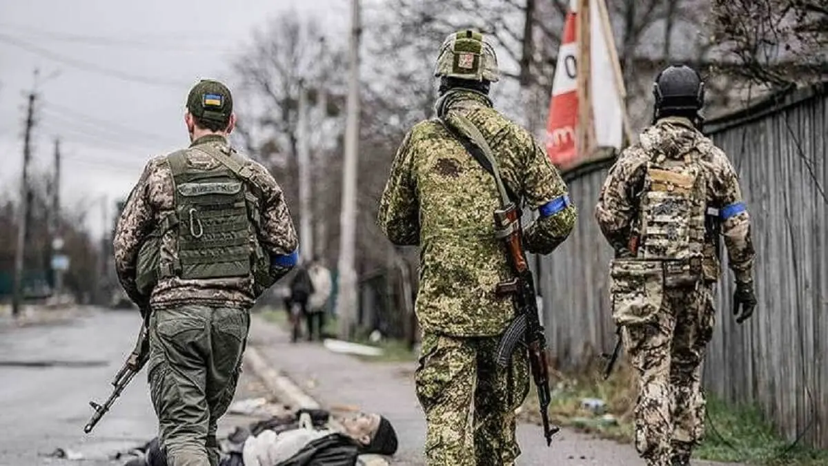 AP/VADIM GHIRDA - Militares ucranianos caminan mientras comprueban los cuerpos de los civiles en busca de trampas explosivas, en el suburbio de Bucha, Ucrania