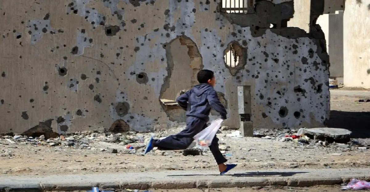 © UNICEF/Giovanni Diffidenti Un niño corre frente a edificios dañados por los bombardeos en la ciudad libia de Sirte