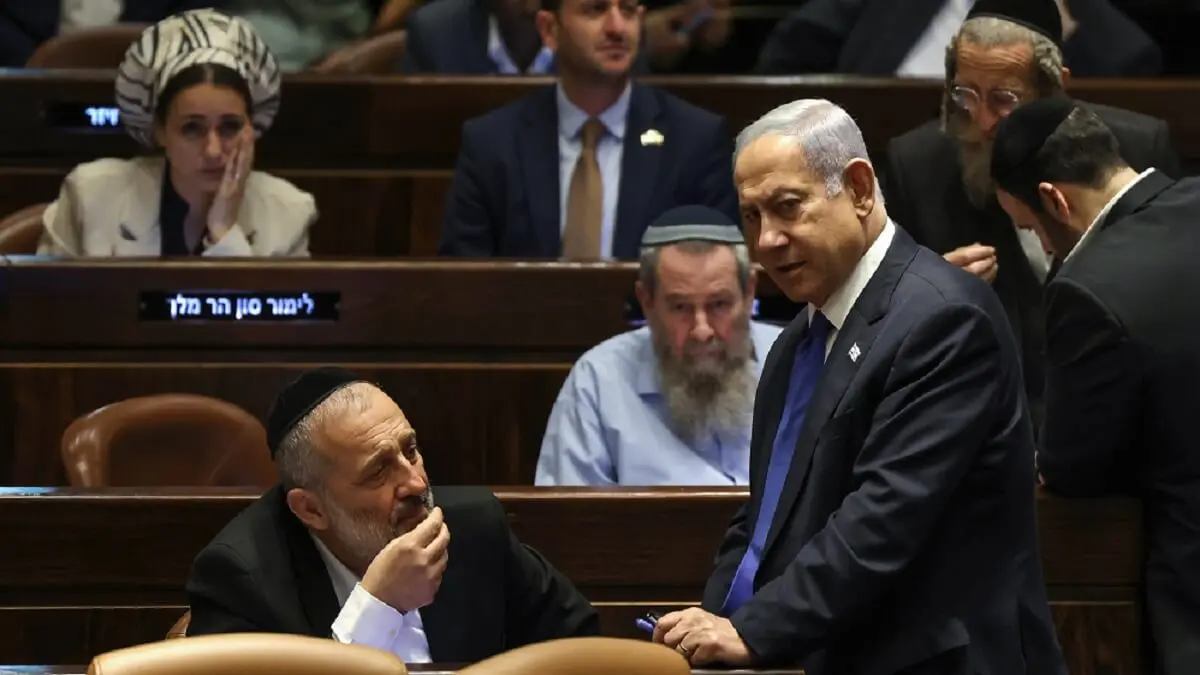 PHOTO/AFP/RONALDO SCHEMIDT - El primer ministro israelí, Benjamin Netanyahu (dcha.), habla con Aryeh Deri (izq.), presidente del partido ultraortodoxo Shas, durante una sesión del Parlamento en Jerusalén el 24 de julio de 2023, en medio de una oleada de protestas contra la reforma judicial prevista por el Gobierno