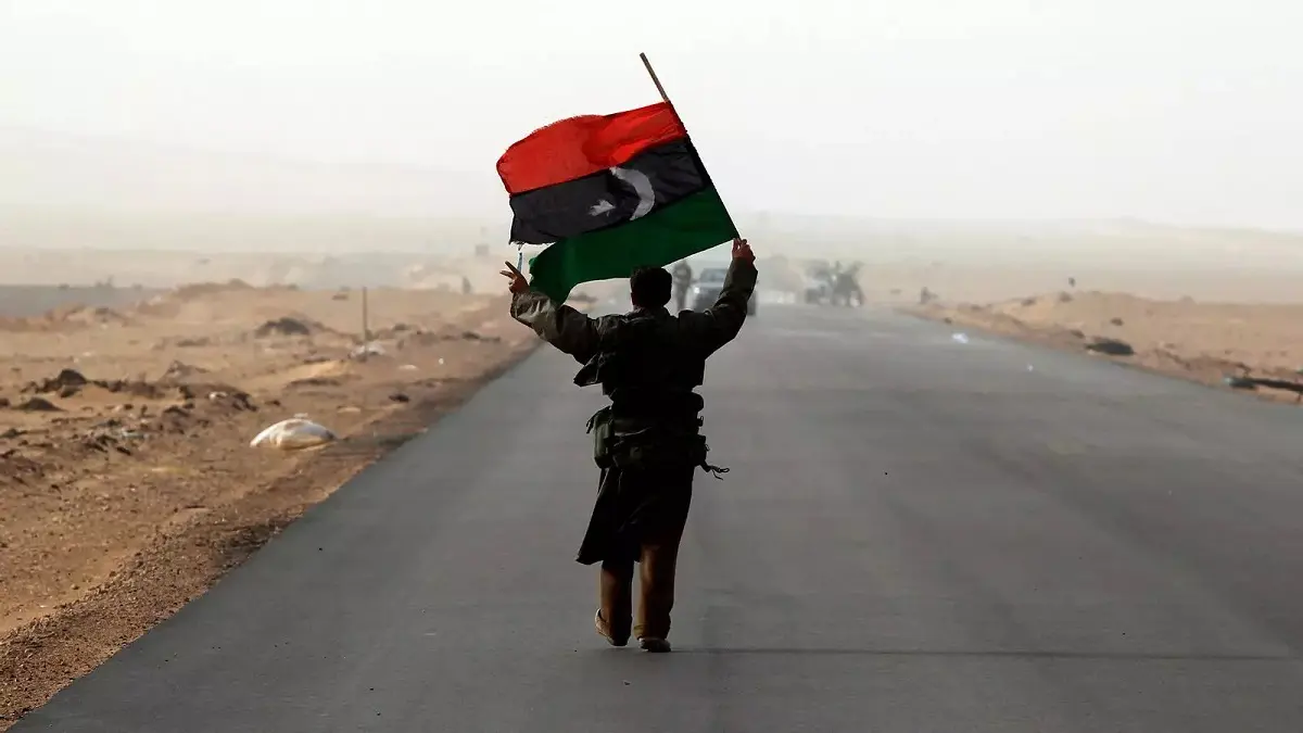 Un hombre con la bandera de Libia durante un bombardeo cerca de la ciudad de Ras Lanuf - PHOTO/REUTERS/GORAN TOMASEVIC