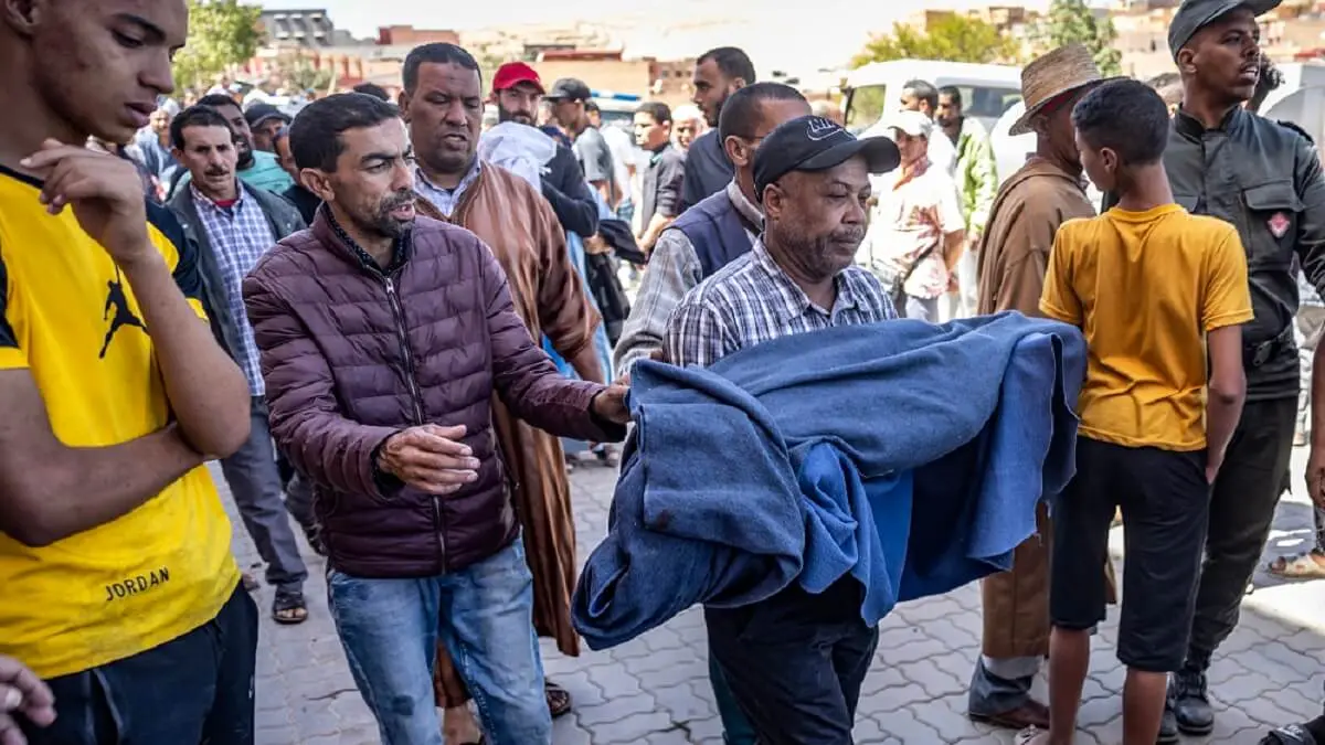 PHOTO/AFP/FADEL SENNA - Un hombre lleva el cuerpo envuelto en una manta de una víctima del terremoto en Moulay Brahim, provincia de Al Haouz, el 9 de septiembre de 2023