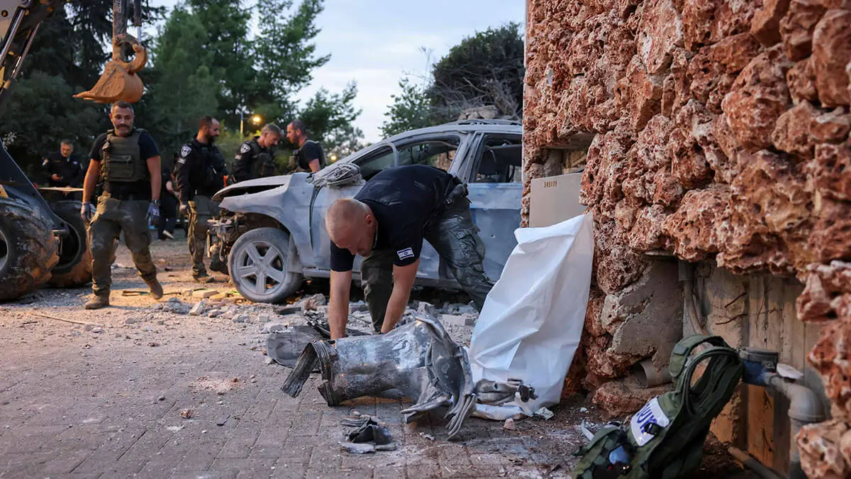 AFP/AHMAD GHARABLI - Las fuerzas de seguridad israelíes inspeccionan un automóvil dañado en un ataque con cohetes desde Gaza en Har Adar, un asentamiento acomodado al noroeste de Jerusalén, en lo alto de las colinas cercanas a la Línea Verde que separa la ocupada Cisjordania de Israel, el 9 de octubre de 2023