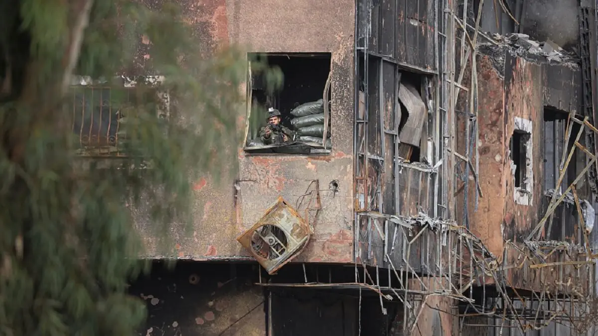 PHOTO/AFP/MAHMUD HAMS - Un soldado israelí toma posiciones dentro de un edificio dañado para vigilar la carretera de Salaheddine