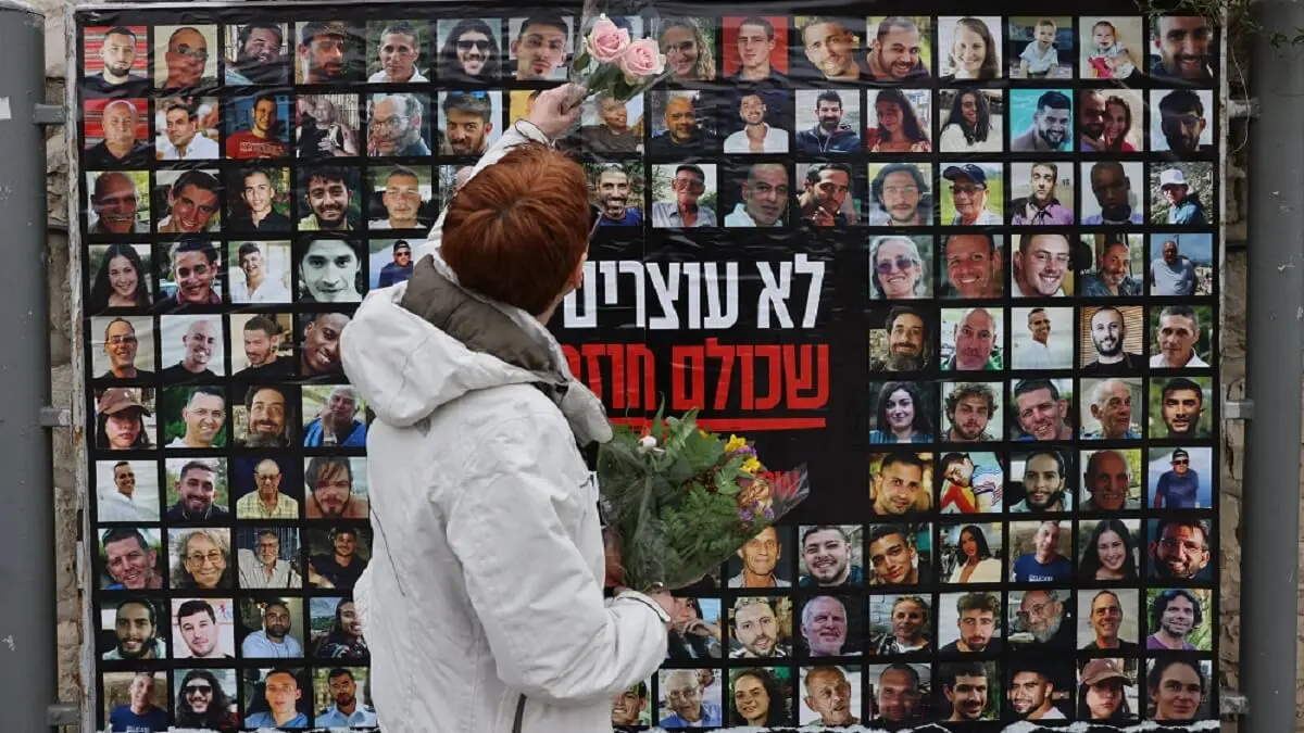 Una mujer cuelga flores sobre un muro con retratos de israelíes cautivos de Hamás en Gaza el 12 de febrero de 2024 en el centro de Jerusalén - PHOTO/AHMAD GHARABLI/AFP