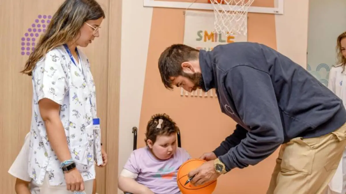 Ricky Rubio firma una pelota a una paciente pediátrica en la nueva Área Terapéutica de Rehabilitación Infantil y Adolescente del Hospital Universitari Vall d'Hebron.© Adrián Quiroga. Fundación "la Caixa"