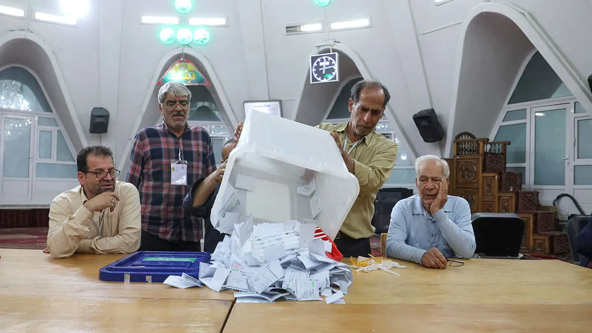 Un miembro del personal electoral vacía las urnas llenas después de que terminó la votación en un centro de votación, en una elección presidencial anticipada para elegir al sucesor de Ebrahim Raisi - WANA/MAJID ASGARIPOUR via REUTERS