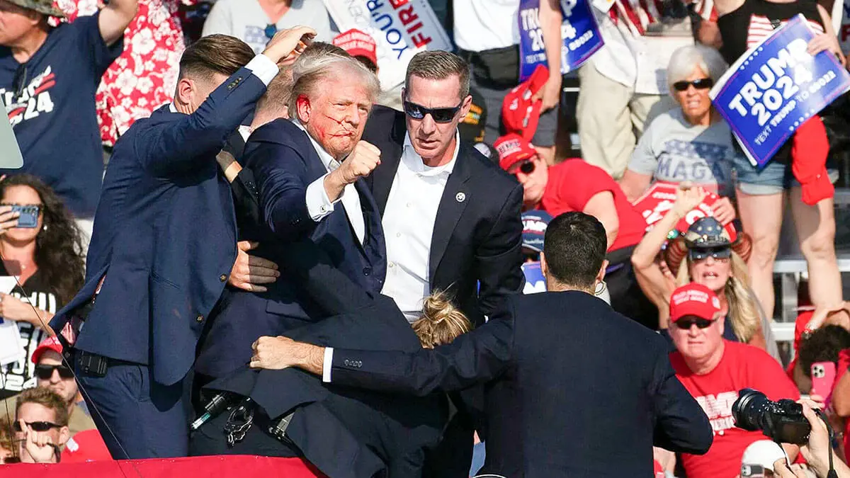 El candidato republicano Donald Trump es visto con sangre en su rostro rodeado de agentes del servicio secreto mientras lo sacan del escenario en un evento de campaña en Butler Farm Show Inc. en Butler, Pensilvania, el 13 de julio de 2024 - AFP/REBECCA DROKE