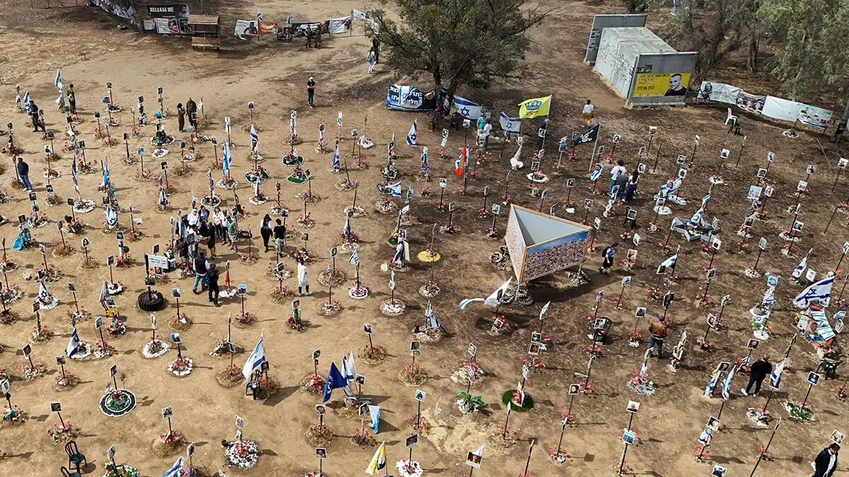 En esta vista aérea, los visitantes caminan alrededor de los retratos de personas que fueron tomadas como rehenes o asesinadas en el ataque de Hamas al festival de música Supernova el 7 de octubre, en el sitio del festival cerca del Kibbutz Reim en el sur de Israel el 13 de mayo de 2024 - AFP/JACK GUEZ