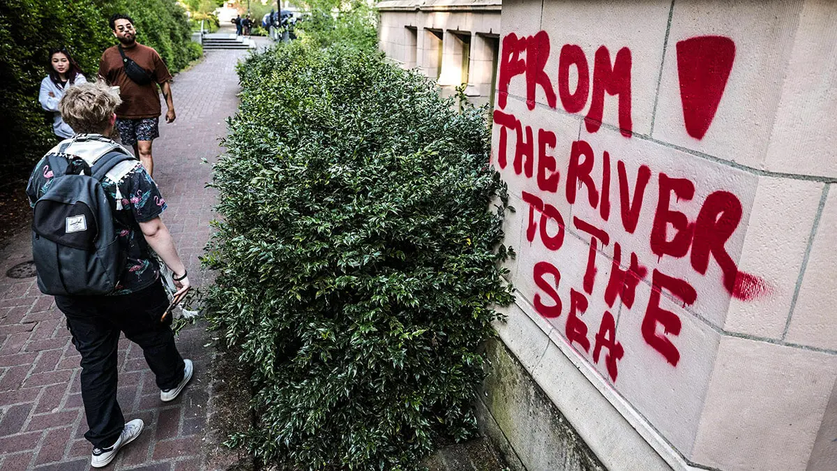 Un grafiti que dice “Del río al mar” se ve en un edificio adyacente a un campamento de protesta contra los vínculos de la Universidad de Washington - AFP/JASON REDMOND