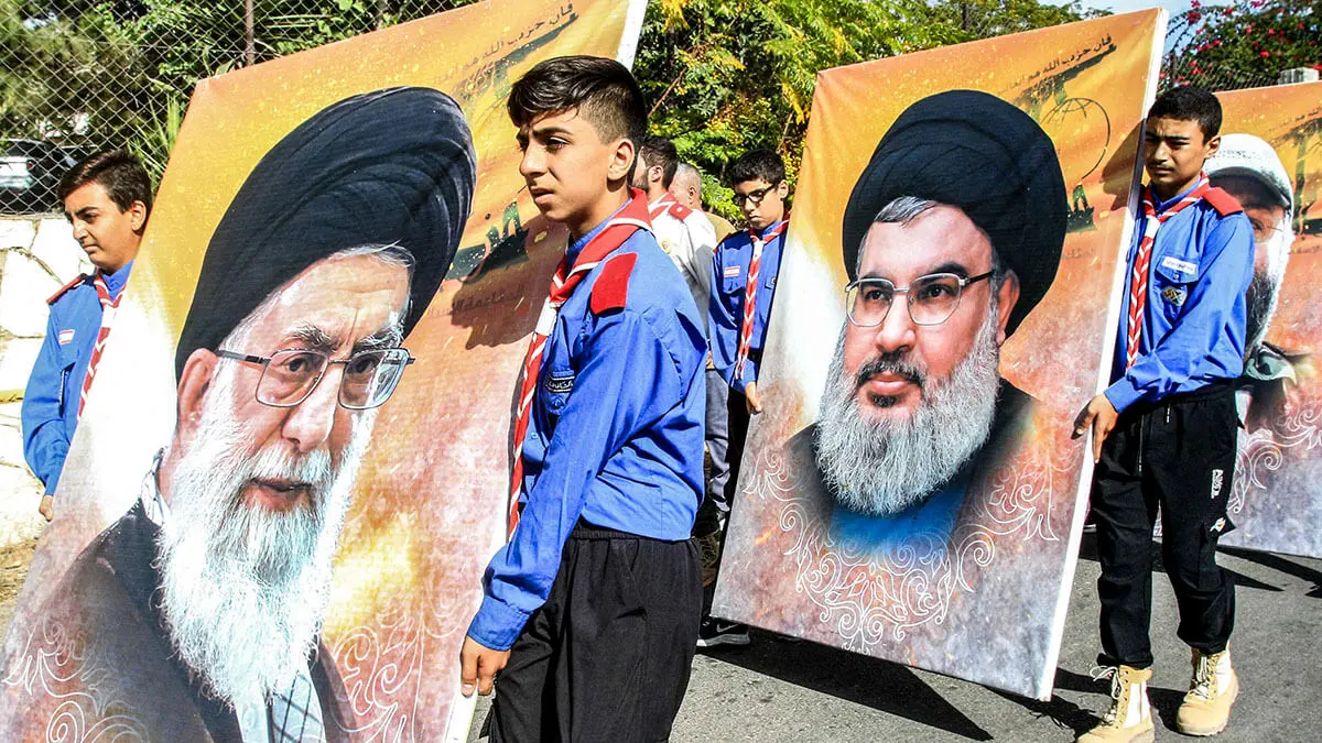 Miembros del movimiento scout afiliados a musulmanes chiíes marchan con grandes retratos que representan al líder supremo de Irán, el ayatolá Ali Jamenei (al frente) y al líder del movimiento chií libanés Hezbolá, Hassan Nasrallah, durante el funeral de un miembro del movimiento chií libanés Hezbolá, en Adloun al sur de Tiro en el sur del Líbano - AFP/MAHMOUD ZAYYAT