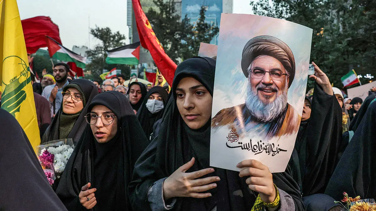 <p>Iraníes sostienen fotografías del líder de Hezbolá, Hassan Nasrallah, quien fue asesinado en un ataque aéreo israelí en los suburbios del sur de Beirut el 27 de septiembre, durante una protesta contra Israel en la Plaza Palestina en Teherán el 30 de septiembre de 2024 - AFP/ ATTA KENARE</p>