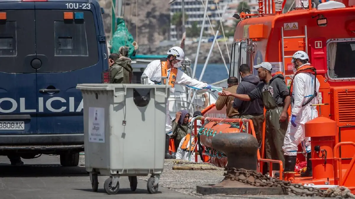 Agentes de la Policía Nacional española entregan máscaras faciales a las personas que desembarcan de un barco después de que varias embarcaciones de migrantes con un total de 18 personas fueran rescatadas frente a la costa de la isla canaria española de Gran Canaria el 14 de septiembre de 2020 - PHOTO/AFP/DESIREE MARTIN