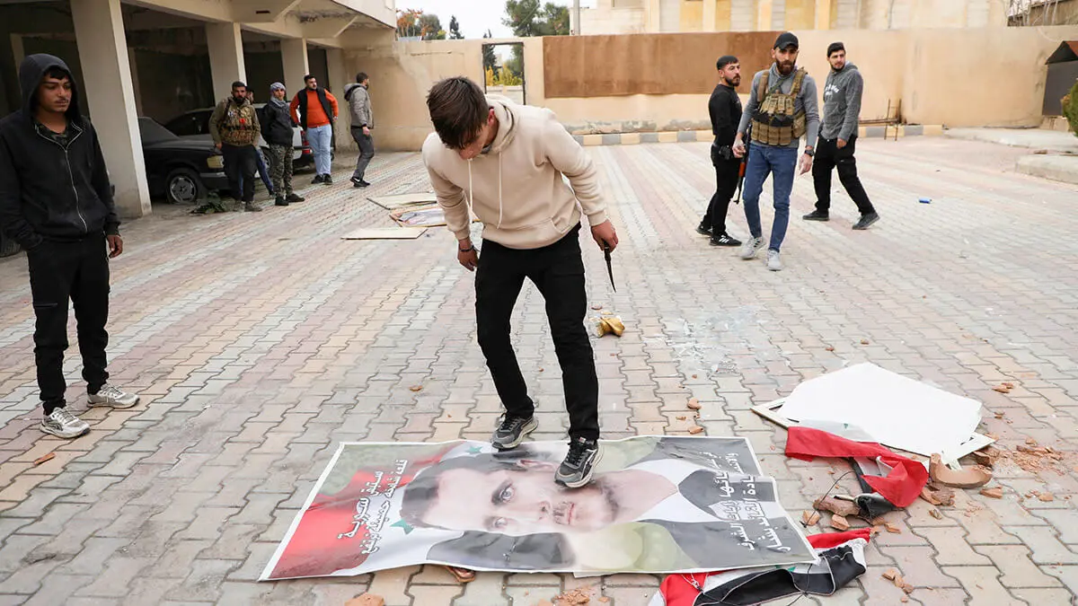 Una persona pasa por encima de una imagen del presidente Bashar al-Assad, después de que los rebeldes tomaran la capital y derrocaran al presidente, en Qamishli, Siria, el 8 de diciembre de 2024 - REUTERS/ ORHAN QUEREMAN