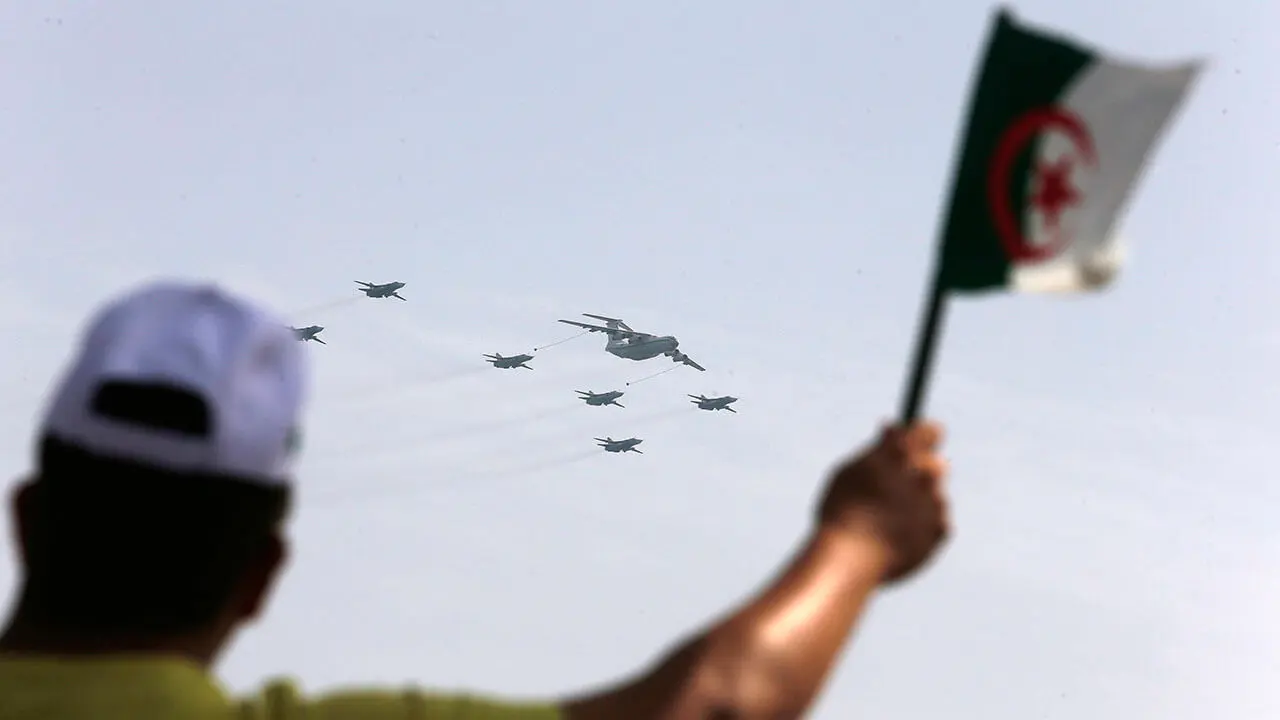 Un hombre ondea una bandera argelina mientras aviones de guerra vuelan durante un desfile militar para conmemorar el 60 aniversario de la independencia de Argelia, el martes 5 de julio de 2022 en Argel - AP/ TOUFIK DOUDOU