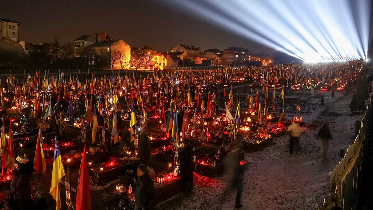 La gente visita las tumbas de sus familiares, que fueron asesinados durante el ataque de Rusia a Ucrania, durante una instalación de luz a gran escala “Luces de la memoria” mientras conmemoran el tercer aniversario de la invasión rusa a gran escala, en el cementerio de Lychakiv en Lviv, Ucrania, el 23 de febrero de 2025 - REUTERS/ROMAN BALUK