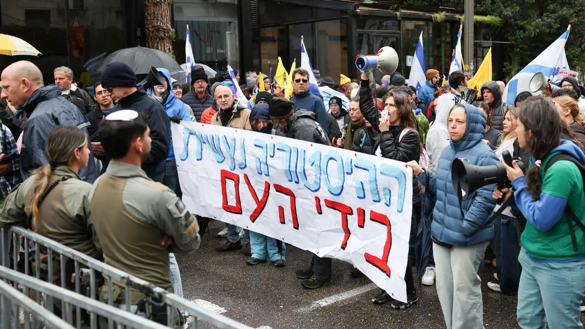 Manifestantes sostienen una pancarta que dice "La historia la hace el pueblo" durante una protesta contra el gobierno israelí y el primer ministro israelí, Benjamin Netanyahu, y exigen la liberación de todos los rehenes de Gaza, cerca de la residencia del primer ministro Netanyahu en Jerusalén, el 21 de marzo de 2025 - REUTERS/ RONEN ZVULUN