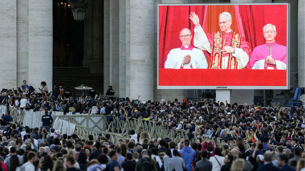 La gente observa mientras el recién elegido papa León XIV, el cardenal Robert Prevost de Estados Unidos, que aparece en la pantalla, aparece en el balcón de la Basílica de San Pedro, visto desde Roma, Italia, el 8 de mayo de 2025 - REUTERS/ ALKIS KONSTANTINIDIS