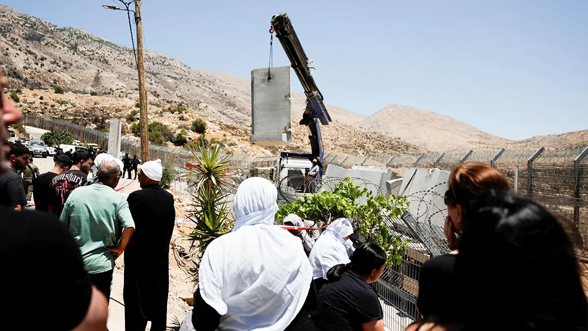 <p>Drusos observan cómo el Ejército israelí coloca un muro de hormigón en la línea de alto el fuego entre los Altos del Golán ocupados por Israel y Siria, en medio del conflicto en curso en las zonas drusas de Siria, en Majdal Shams, el 17 de julio de 2025 - REUTERS/ AMMAR AWAD </p>