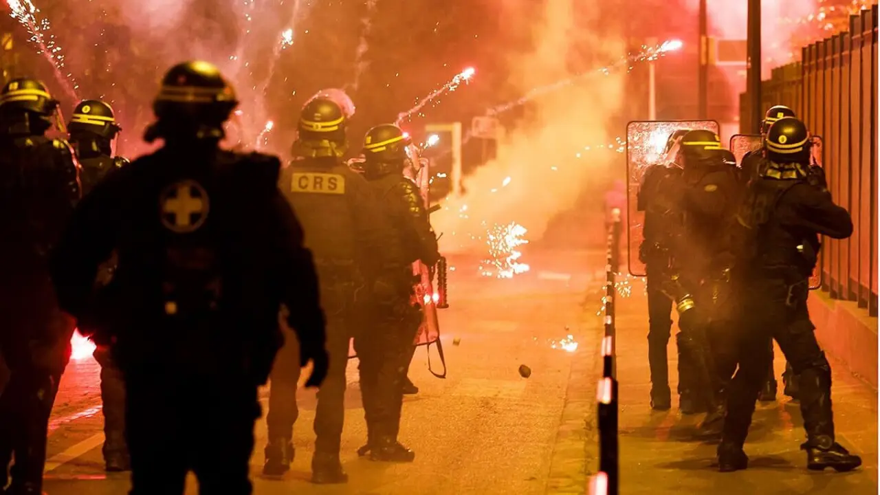 REUTERS/GONZALO FUENTES - La Policía francesa permanece en posición mientras estallan fuegos artificiales durante los enfrentamientos con jóvenes, después de la muerte de Nahel, un adolescente de 17 años asesinado por un oficial de policía francés durante una parada de tráfico, en Nanterre, suburbio de París, Francia, 30 de junio de 2023