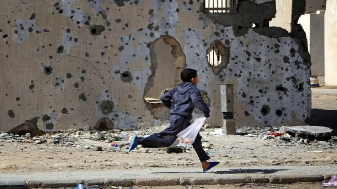 © UNICEF/Giovanni Diffidenti Un niño corre frente a edificios dañados por los bombardeos en la ciudad libia de Sirte