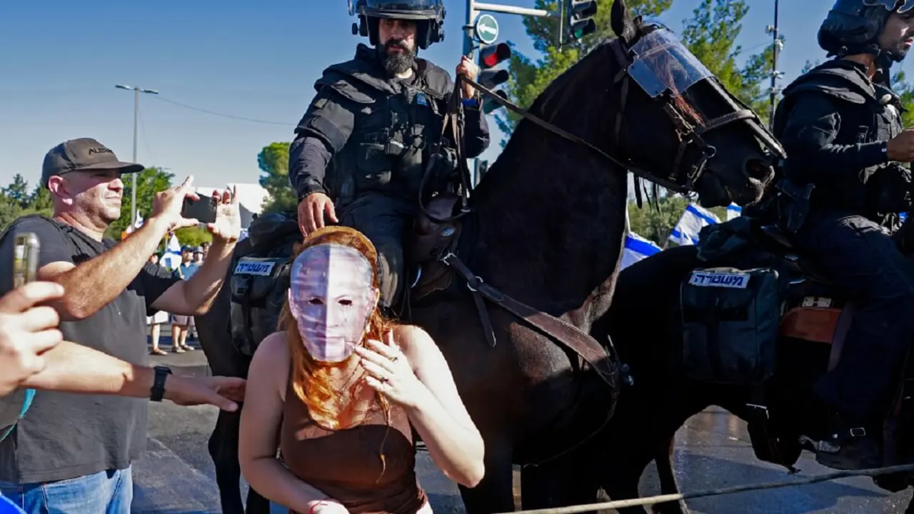 PHOTO/AFP/MENAHEM KAHANA - Miembros de la policía montada de Israel se acercan a un manifestante con una máscara que representa al primer ministro Benjamin Netanyahu mientras dispersan una manifestación ante el Parlamento (Knesset) en Jerusalén el 24 de julio de 2023