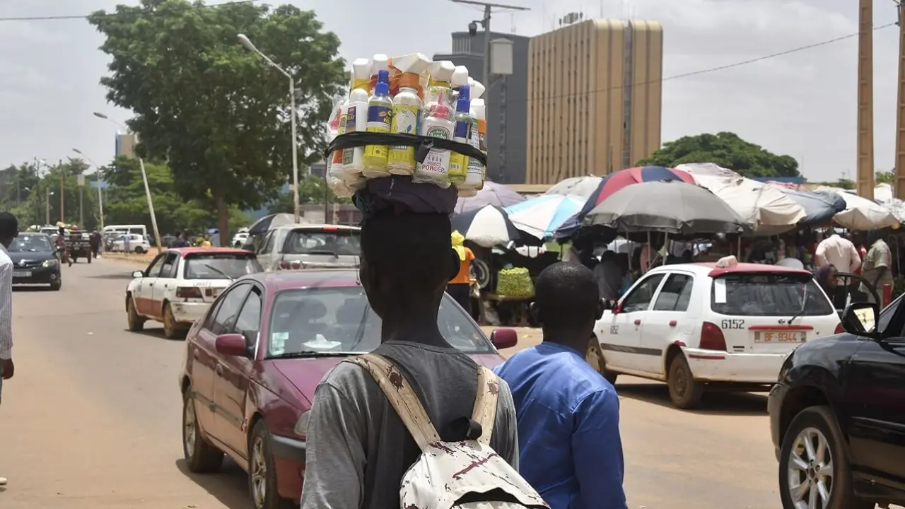 PHOTO/AFP/BOUREIMA HAMA - Un vendedor ambulante camina junto a una calle que parece tranquila con tráfico normal en Niamey el 26 de julio de 2023 mientras el presidente nigeriano Mohamed Bazoum es retenido por guardias según una fuente cercana a Bazoum