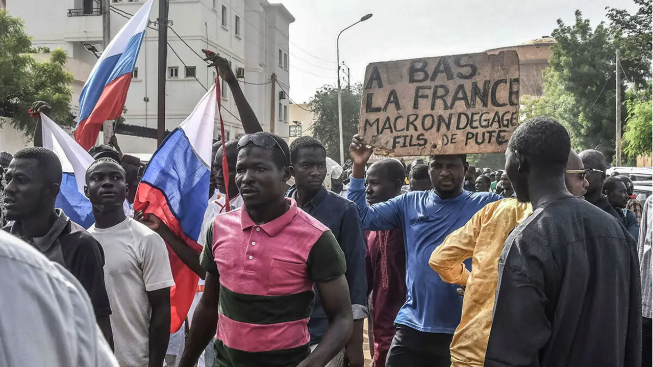 PHOTO/AFP - Varios simpatizantes ondean banderas rusas y una pancarta con un lema contra Francia mientras se manifiestan en apoyo de la junta nigerina en Niamey el 30 de julio de 2023
