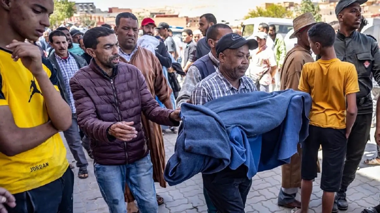 PHOTO/AFP/FADEL SENNA - Un hombre lleva el cuerpo envuelto en una manta de una víctima del terremoto en Moulay Brahim, provincia de Al Haouz, el 9 de septiembre de 2023