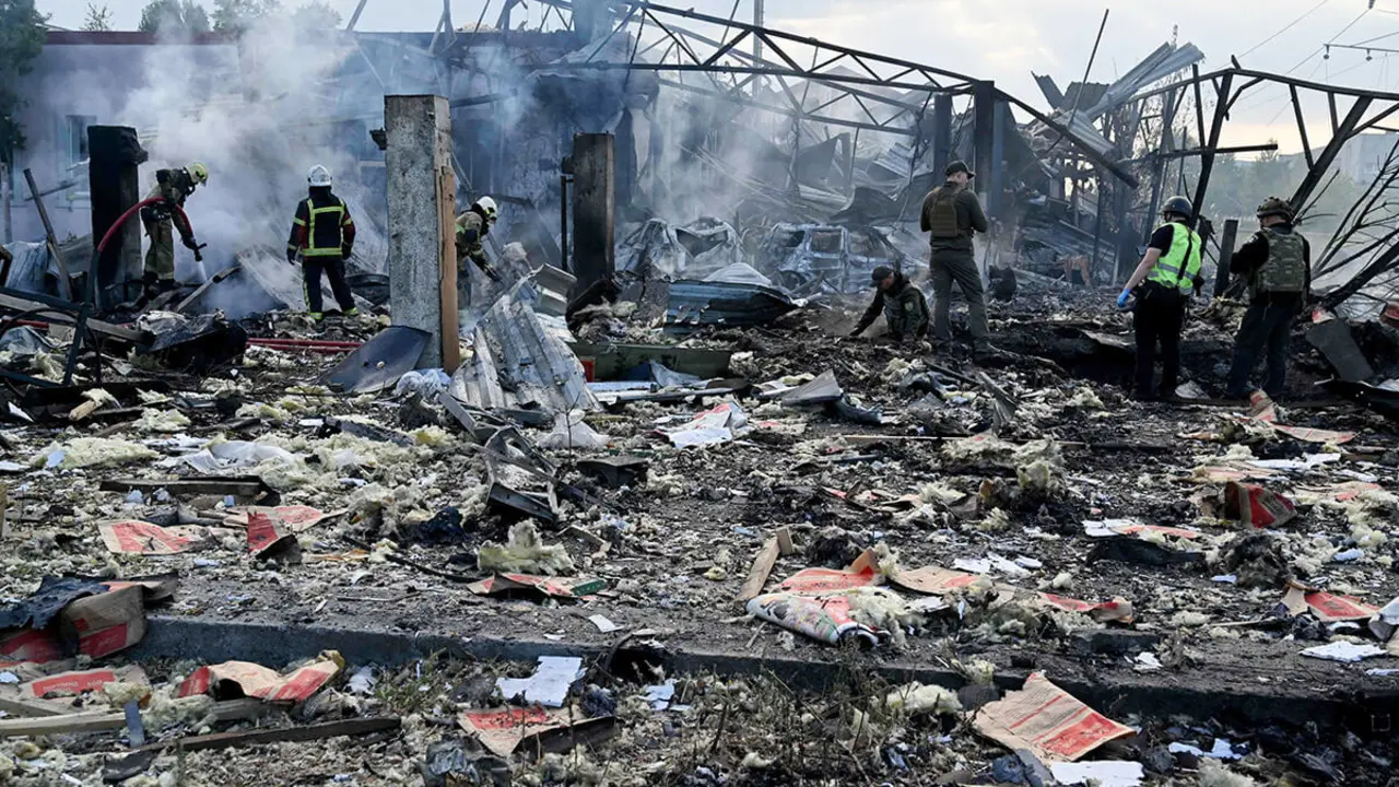 Los bomberos apagan un incendio mientras los expertos de la policía buscan fragmentos de misil en un cráter en una zona industrial de la capital ucraniana de Kiev, después de un ataque masivo con misiles durante la noche a Ucrania el 21 de septiembre - AFP/SERGEI SUPINSKY