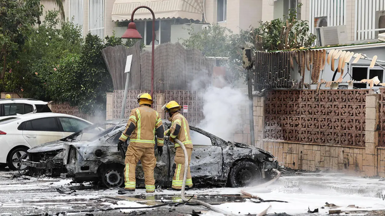 Los bomberos apagan una llama en un automóvil en la ciudad de Ashdod, en el sur de Israel, el 9 de octubre de 2023, después de que cohetes disparados desde Gaza impactaran en la ciudad 

AFP/AHMAD GHARABLI