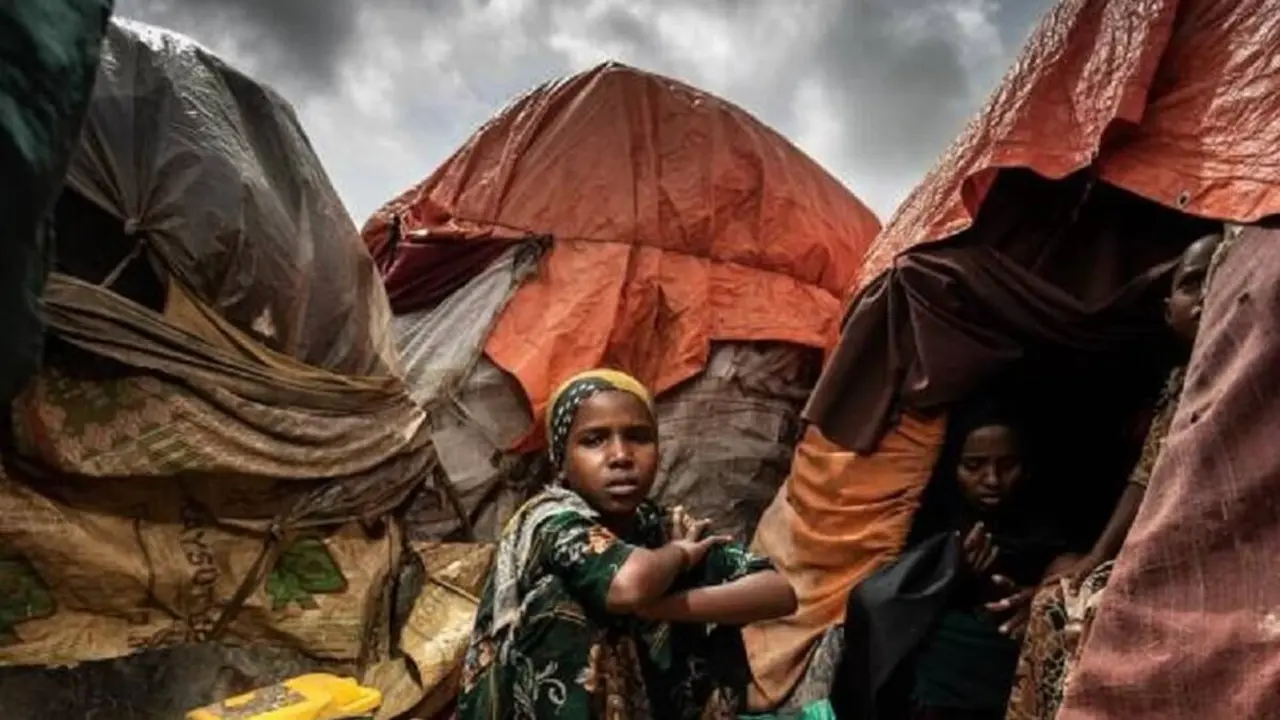 UNICEF/UN0742088/Condren - Una niña sentada frente a la tienda de campaña en la que vive su familia en un campo de desplazados internos en Mogadiscio, Somalia, en octubre de 2022