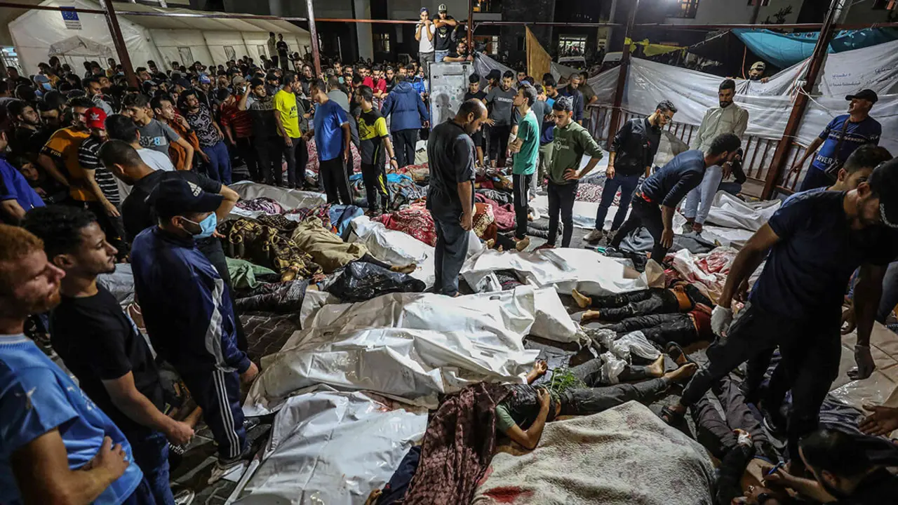 La gente se reúne alrededor de los cuerpos de palestinos asesinados después de una explosión que arrasó el hospital Ahli Arab en el centro de Gaza después de que fueron transportados al hospital Al-Shifa, el 17 de octubre de 2023 - AFP/DAWOOD NEMER