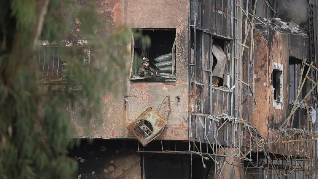 PHOTO/AFP/MAHMUD HAMS - Un soldado israelí toma posiciones dentro de un edificio dañado para vigilar la carretera de Salaheddine