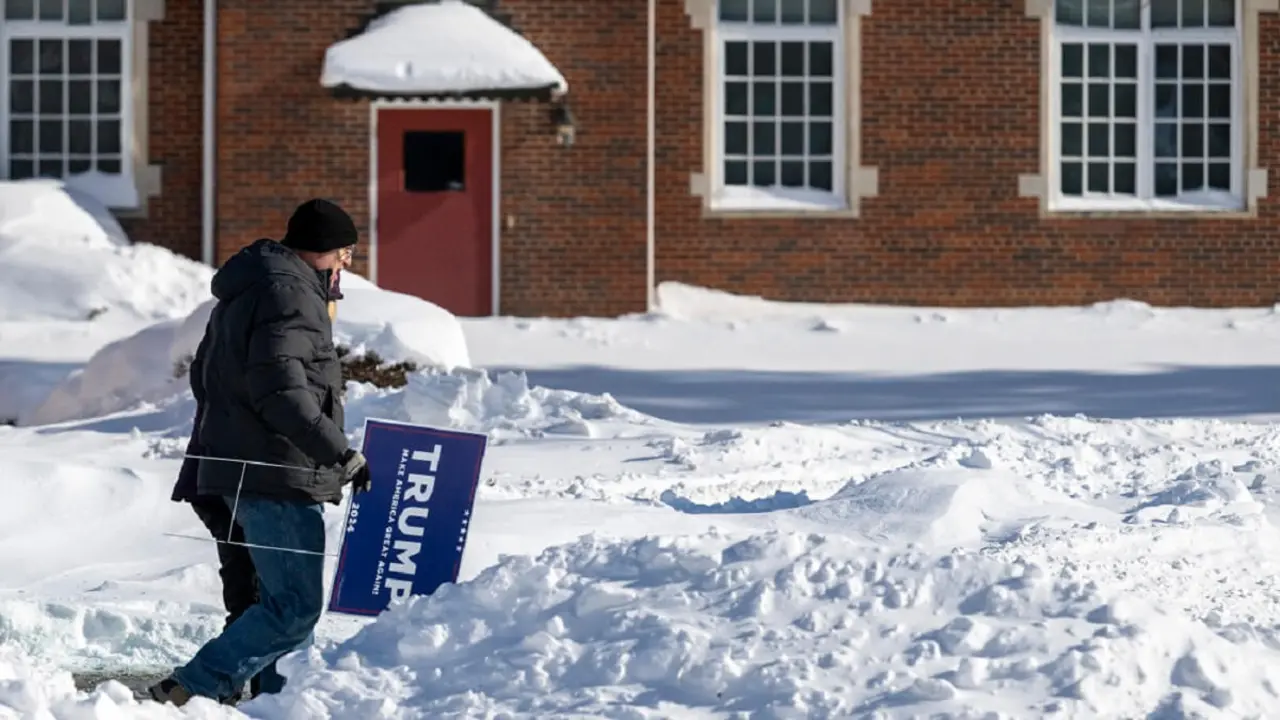 Un seguidor del expresidente de Estados Unidos y aspirante a la presidencia en 2024 Donald Trump porta una pancarta de Trump mientras desafía las temperaturas bajo cero para asistir a un mitin en Indianola, Iowa, el 14 de enero de 2024 – PHOTO/Jim WATSON/AFP