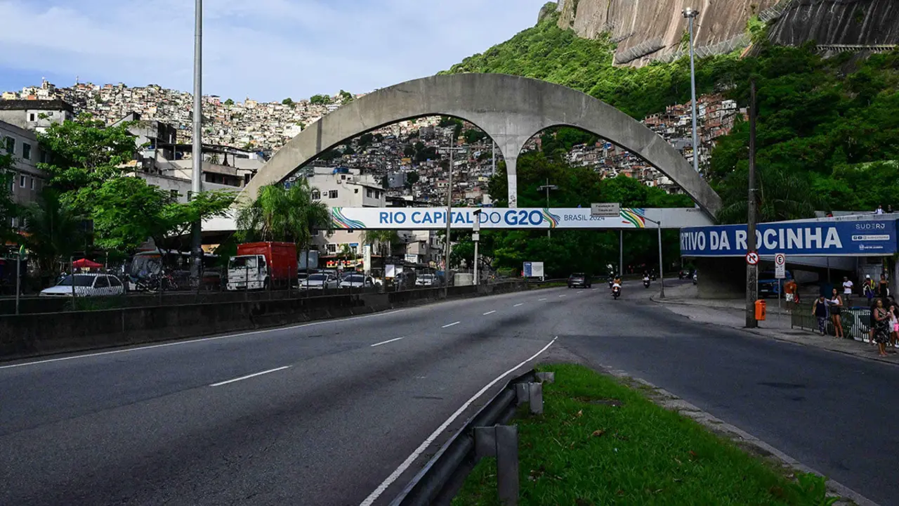 Un cartel del G20 Brasil se instala en un puente frente al barrio de Rocinha en Río de Janeiro, Brasil, el 15 de febrero de 2024 - AFP/PABLO PORCIUNCULA