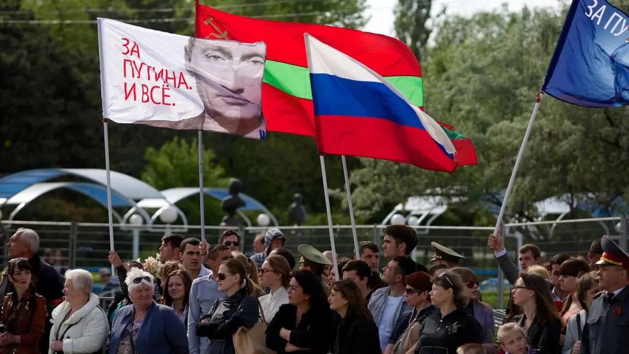 Varias personas portan una bandera rusa y una bandera con un retrato del presidente de Rusia, Vladimir Putin, en la que se lee “¡Estamos con Putin!” en Tiraspol, la principal ciudad de la región separatista de Moldavia de Transnistria – PHOTO/VADIM DENISOV/AFP