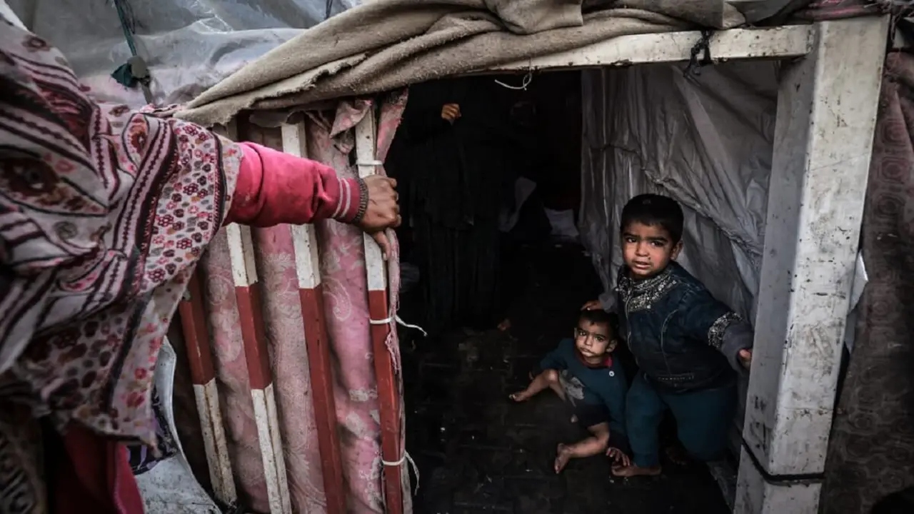 Niños palestinos desplazados esperan en el interior de sus tiendas improvisadas en un campamento junto a una calle de Rafah el 14 de marzo de 2024, en medio de los combates en curso entre Israel y el grupo militante Hamás – PHOTO/Mohammed ABED/AFP