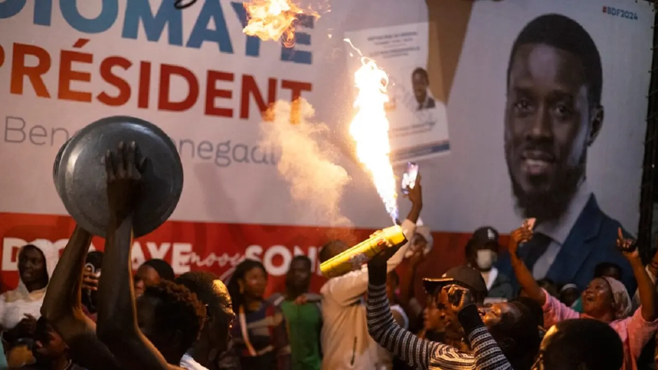 Simpatizantes del candidato presidencial de la oposición Bassirou Diomaye Faye y del líder de la oposición Ousmane Sonko celebran en la sede de la coalición de Diomaye mientras se cuentan los votos, en Liberte 4, Dakar, el 24 de marzo de 2024 durante las elecciones presidenciales senegalesas - PHOTO/MARCO LONGARI/AFP