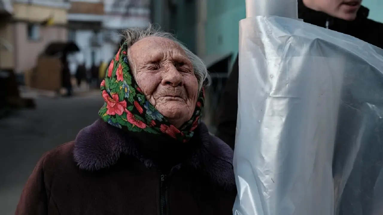 Una anciana recoge plásticos para tapar las ventanas de su casa, arrancadas tras un bombardeo ruso en Kiev a finales de marzo - PHOTO/MARÍA SENOVILLA