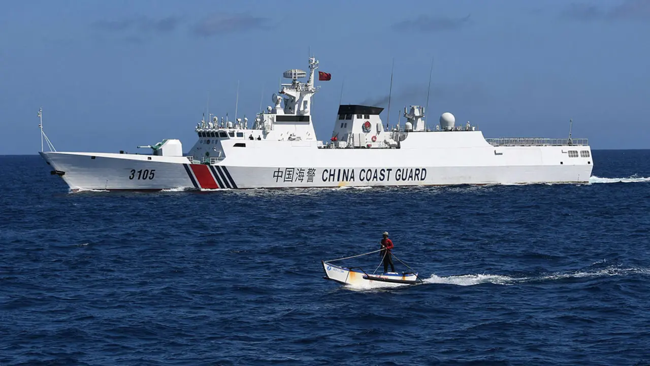 Un pescador filipino (al frente) navegando junto a un barco guardacostas chino cerca del Scarborough Shoal controlado por China, en aguas en disputa del Mar de China Meridional - AFP/TED ALIBE