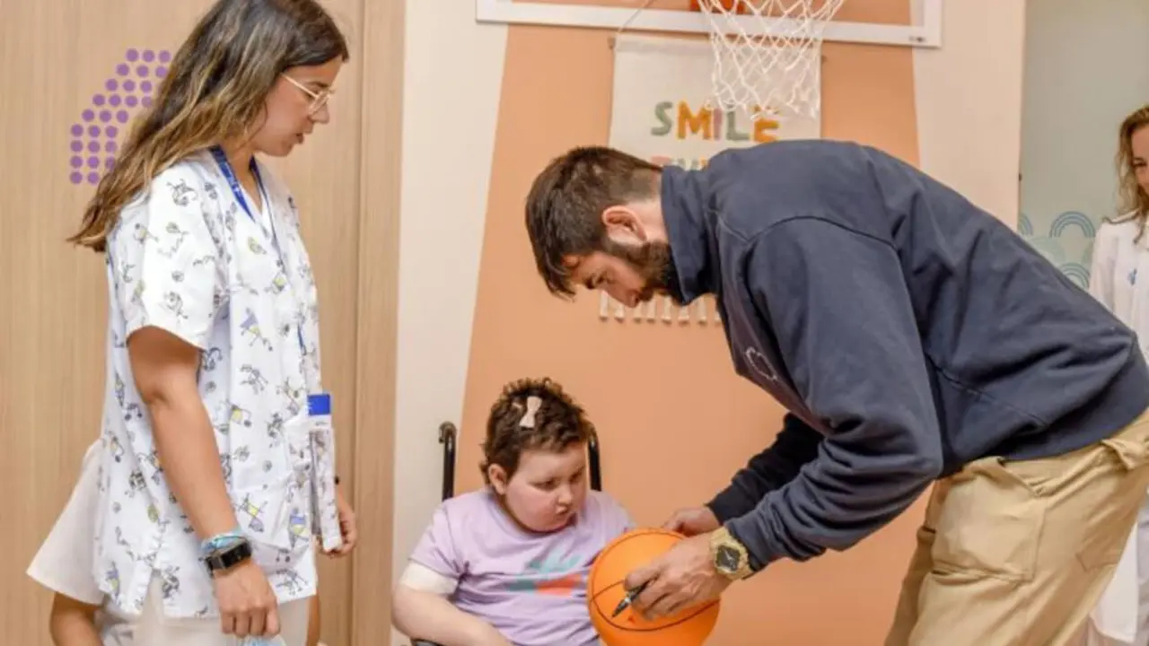 Ricky Rubio firma una pelota a una paciente pediátrica en la nueva Área Terapéutica de Rehabilitación Infantil y Adolescente del Hospital Universitari Vall d'Hebron.© Adrián Quiroga. Fundación "la Caixa"