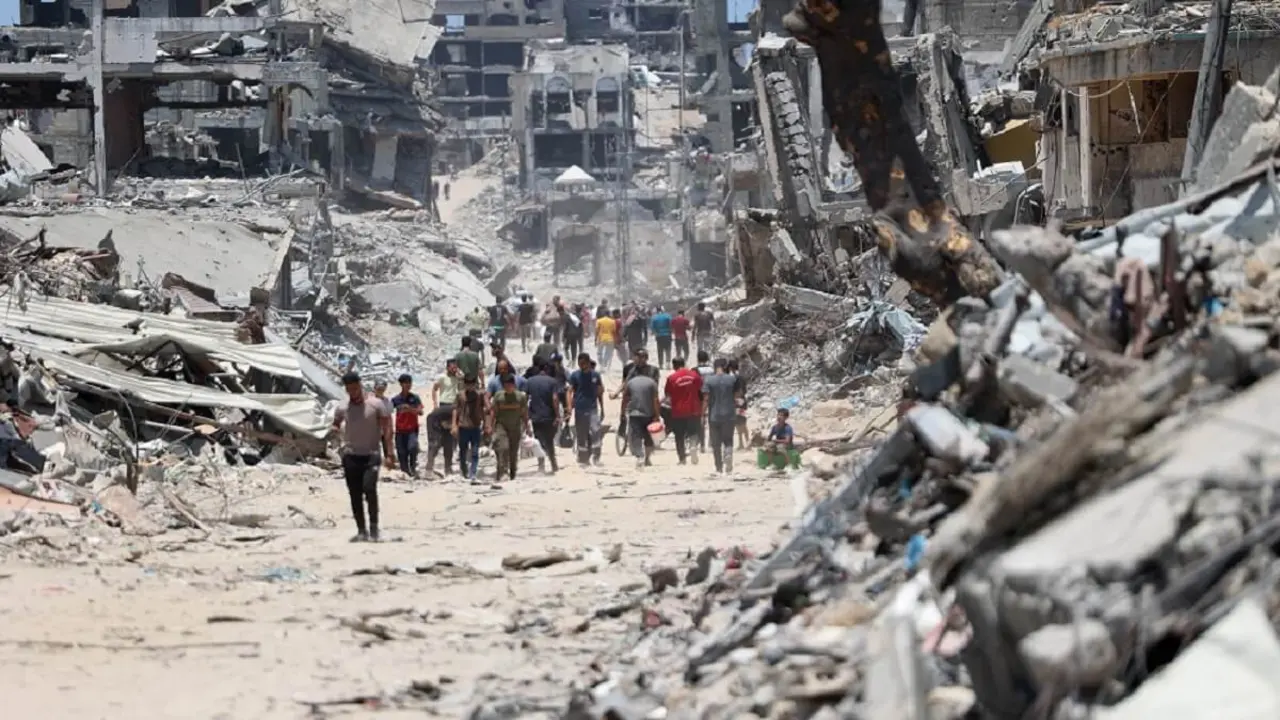 El 11 de julio de 2024, palestinos se abren paso entre los escombros de edificios destruidos tras la retirada del Ejército israelí del barrio de Shujaiya, al este de la ciudad de Gaza, después de una ofensiva de dos semanas, en medio del actual conflicto entre Israel y el grupo militante Hamás – PHOTO/Omar AL-QATTAA/AFP
