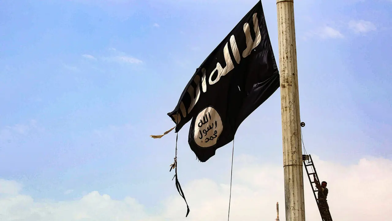 Un miembro de las Fuerzas Democráticas Sirias (FDS), respaldadas por Estados Unidos y formadas por una alianza de combatientes árabes y kurdos, retira una bandera del grupo Daesh en la ciudad de Tabqa, a unos 55 kilómetros (35 millas) al oeste de la ciudad de Raqa - AFP/DELIL SOULEIMAN