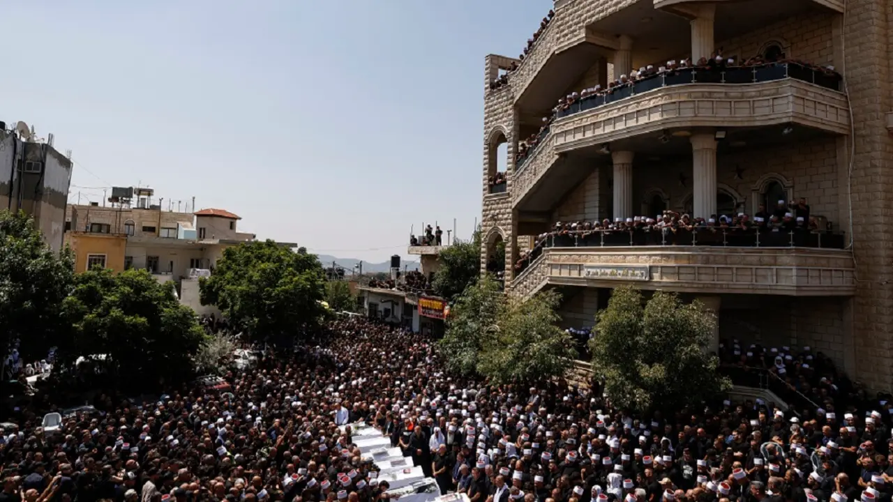 Ancianos drusos y dolientes rodean los ataúdes de 10 de las 12 personas muertas en un ataque con cohetes desde Líbano un día antes, durante un funeral multitudinario en la ciudad drusa de Majdal Shams, en los Altos del Golán anexionados por Israel, el 28 de julio de 2024 – PHOTO/Jalaa MAREY/AFP