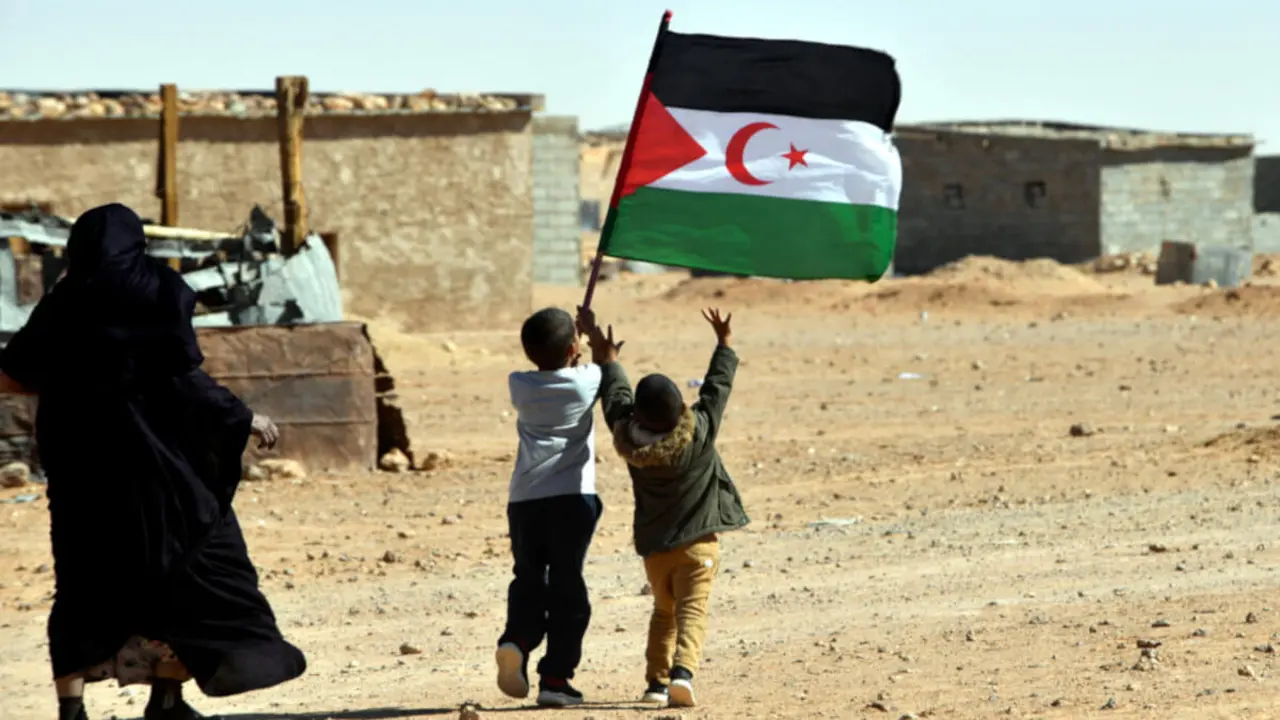 Un niño iza la bandera de la República Árabe Saharaui Democrática (RASD) durante las celebraciones del 47 aniversario de la declaración de unidad nacional del pueblo saharaui, en el campamento de refugiados de Aousserd, a las afueras de la ciudad de Tinduf, en el suroeste de Argelia, el 12 de octubre de 2022 - PHOTO/RYAD KRAMDI / AFP