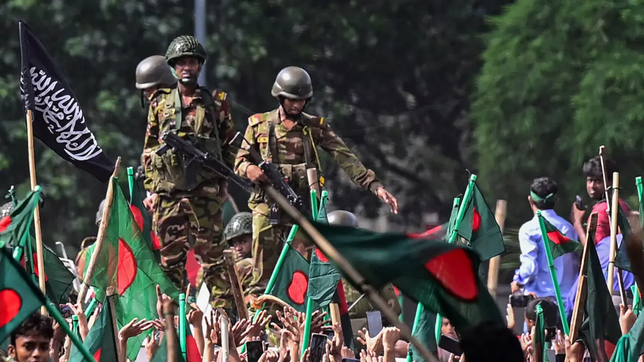 Manifestantes antigubernamentales marchan hacia el palacio de la primera ministra Sheikh Hasina mientras personal del ejército (C) hace guardia en el área de Shahbag, cerca de la universidad de Dhaka en Dhaka el 5 de agosto de 2024 - Munir UZ ZAMAN / AFP