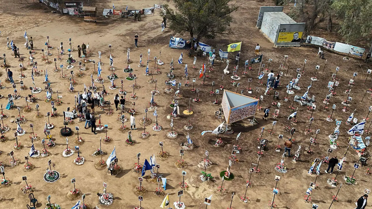 En esta vista aérea, los visitantes caminan alrededor de los retratos de personas que fueron tomadas como rehenes o asesinadas en el ataque de Hamas al festival de música Supernova el 7 de octubre, en el sitio del festival cerca del Kibbutz Reim en el sur de Israel el 13 de mayo de 2024 - AFP/JACK GUEZ