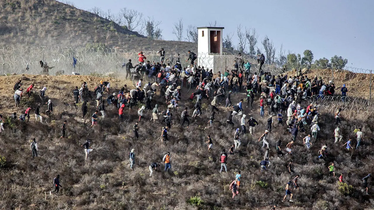 <p>Asalto de una valla de alambre de púas mientras intentan cruzar la frontera terrestre con el enclave africano de España, Ceuta, cerca de Fnideq, en el norte de Marruecos, el 15 de septiembre de 2024 - PHOTO/AFP</p>
