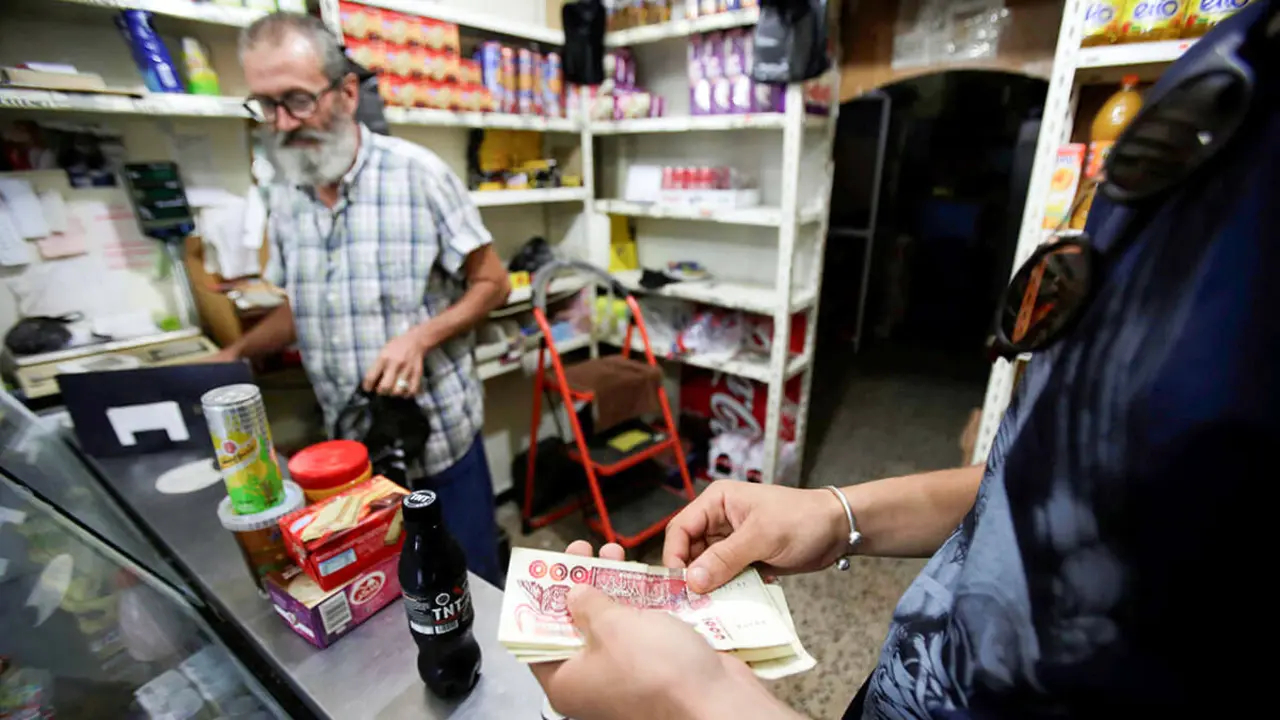 Un cliente le da dinero a un vendedor en una tienda de comestibles en Argel, Argelia - REUTERS/ RAMZI BOUDINA